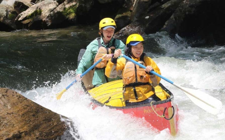 two gap year students paddle a canoe through whitewater on an outward bound expedition in north carolina 